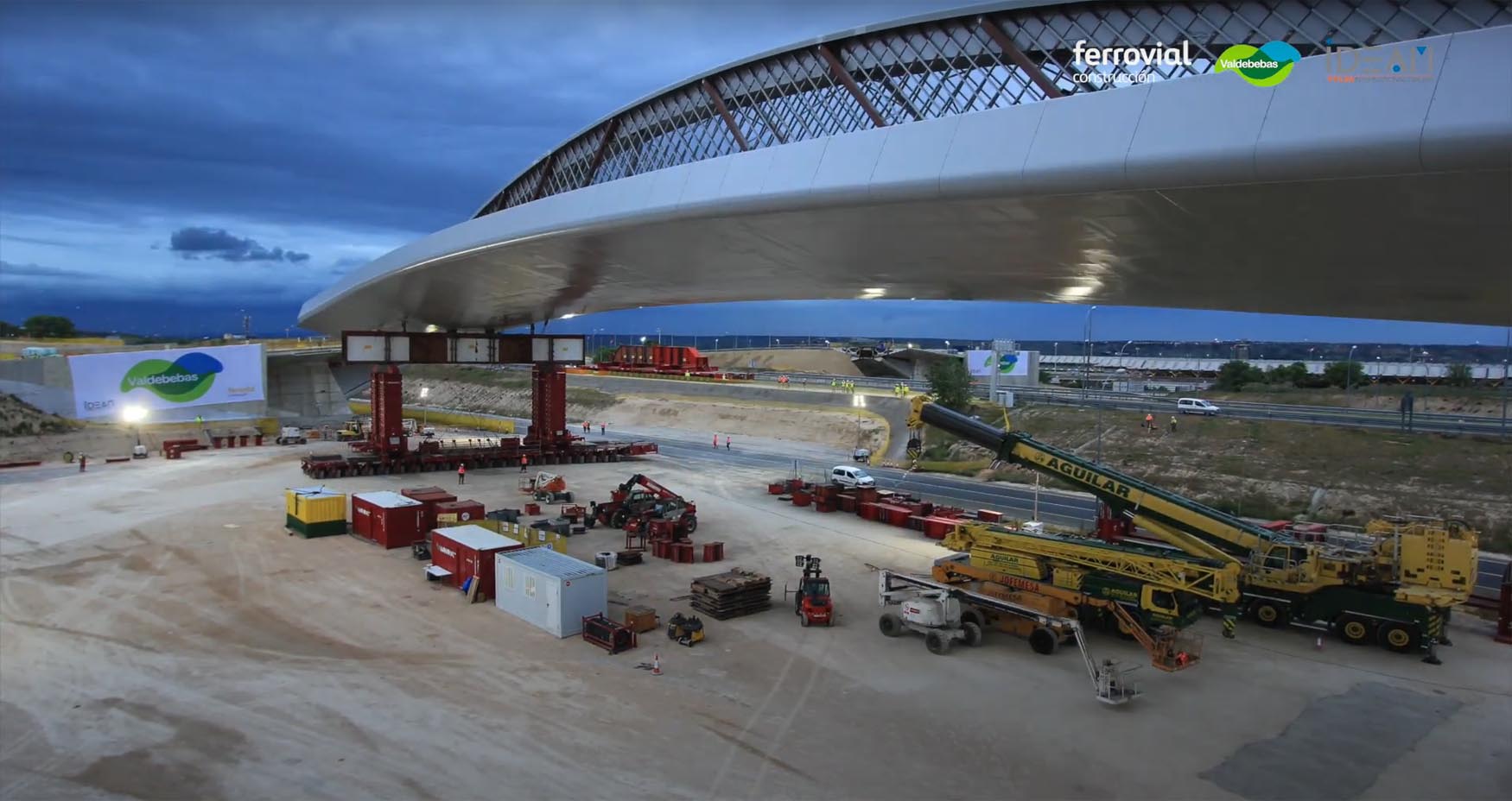 A unique 128.6m-long steel arch is transported near Madrid Airport logo 